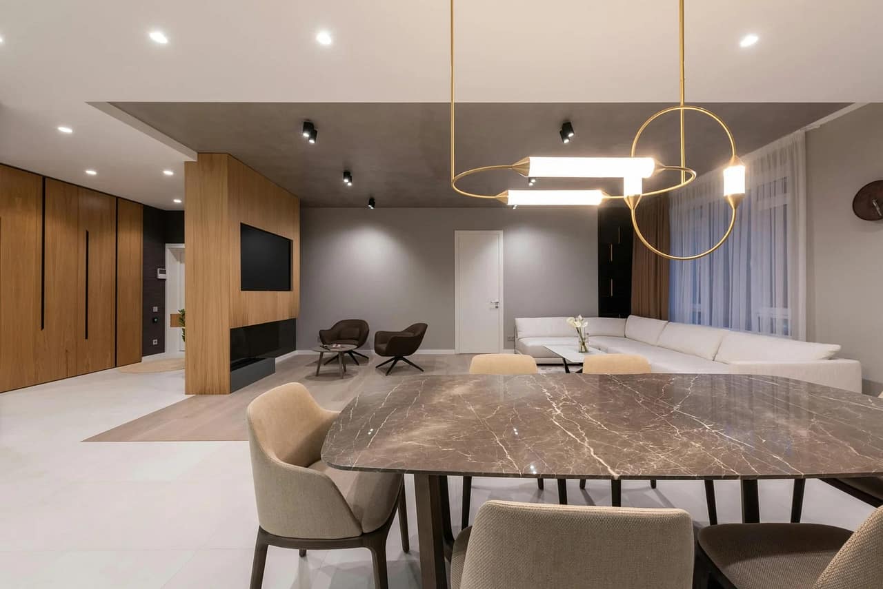 pexels photo 6758776 6758776 Interior of modern light home with dining table with chairs under lamps hanging on ceiling next to sofa near windows with curtains and armchairs with TV on wall